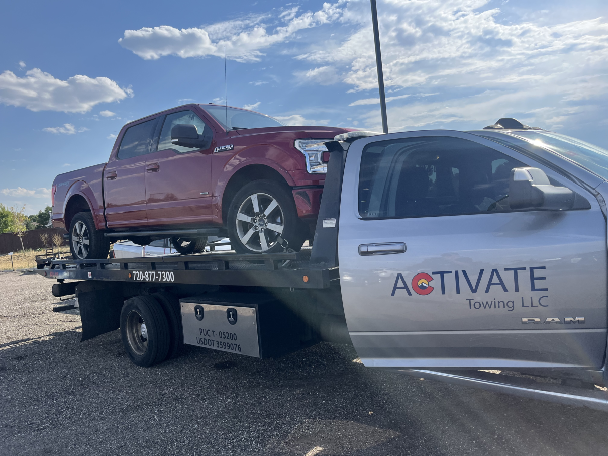 Activate Towing flatbed loaded with a red Ford F-150 pickup near Elizabeth, Colorado